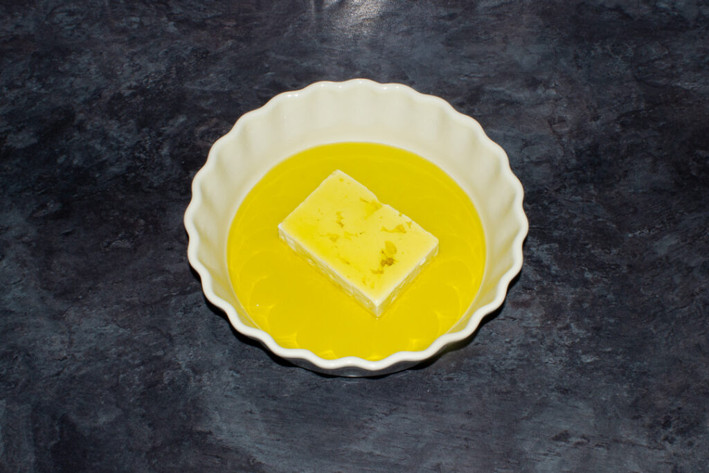 A block of feta covered in olive oil in an ovenproof dish