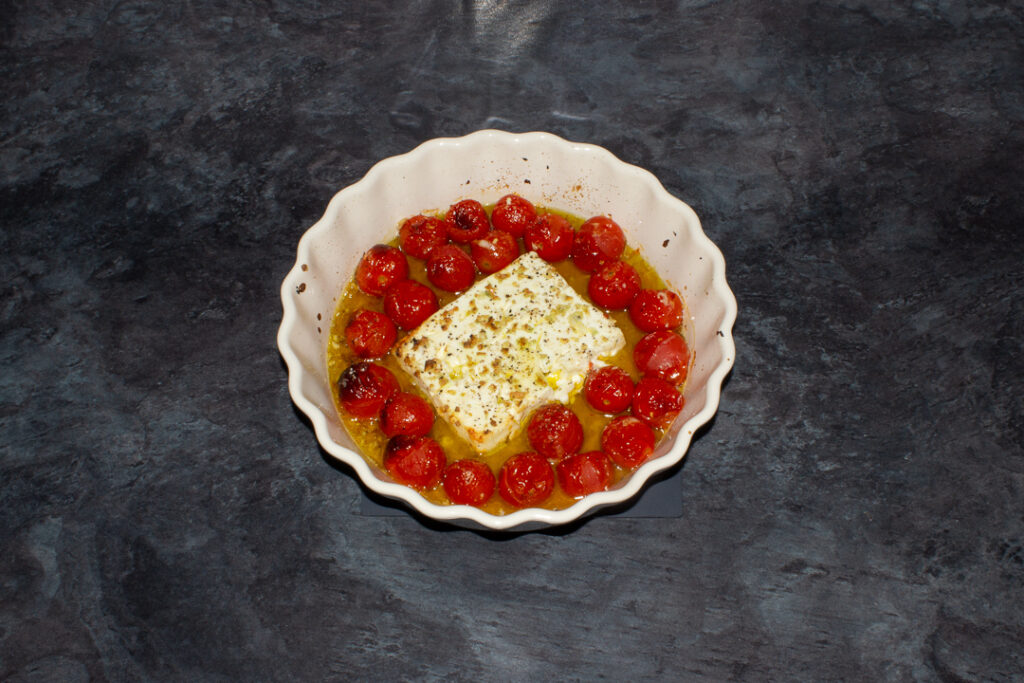 Unmixed baked feta tomato pasta sauce in an ovenproof dish