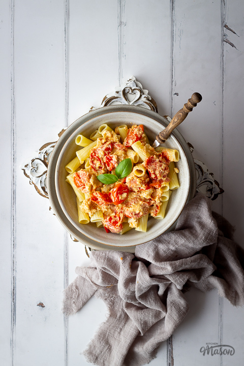 A bowl of feta tomato pasta with a fork and a linen napkin