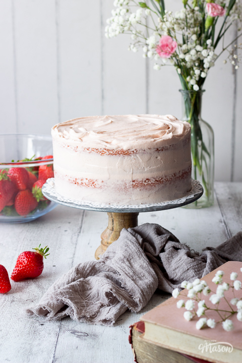 A frosted strawberry cake on a cake stand