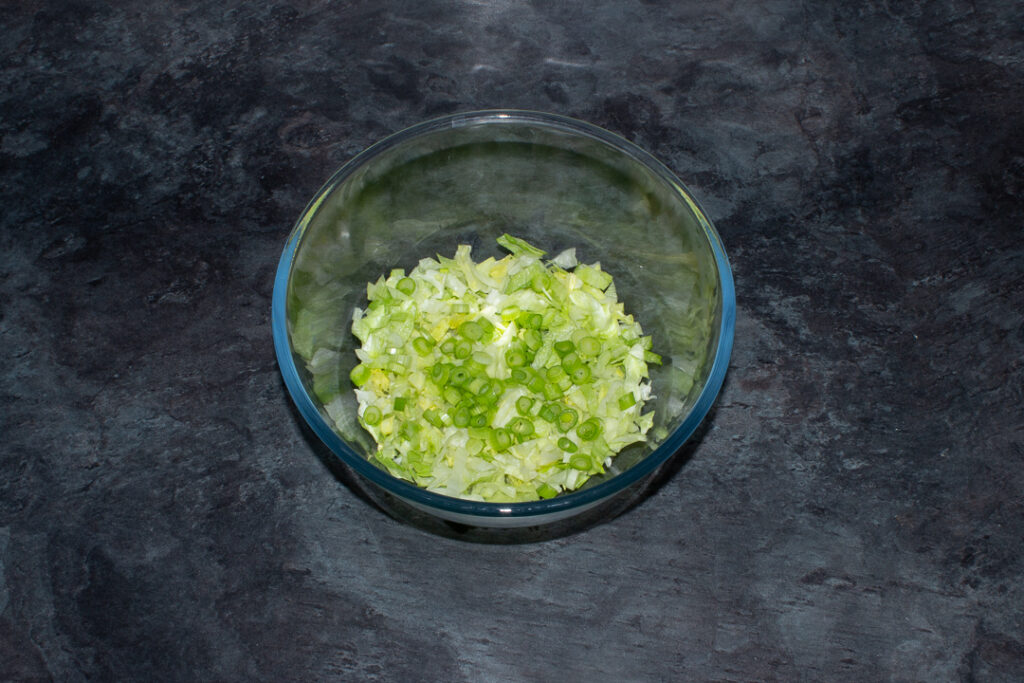 Chopped lettuce and spring onion in a mixing bowl