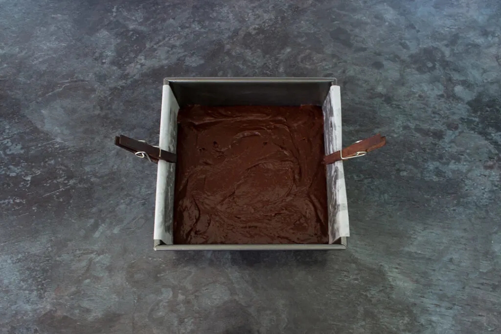 Chocolate brownie batter in a square baking tin