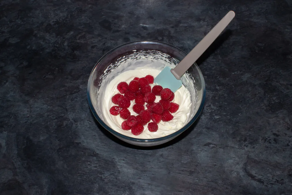 Raspberries being folded into sweetened cream.