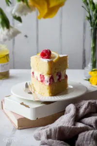 Front view of a slice of lemon and raspberry cake on a plate.