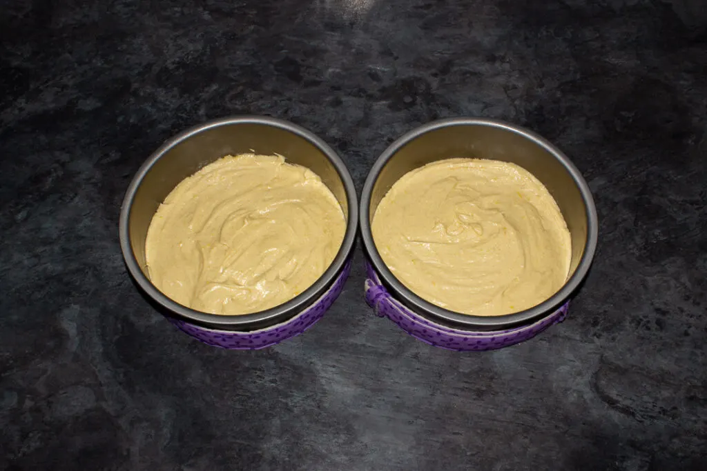 Cake batter in two lined baking tins.