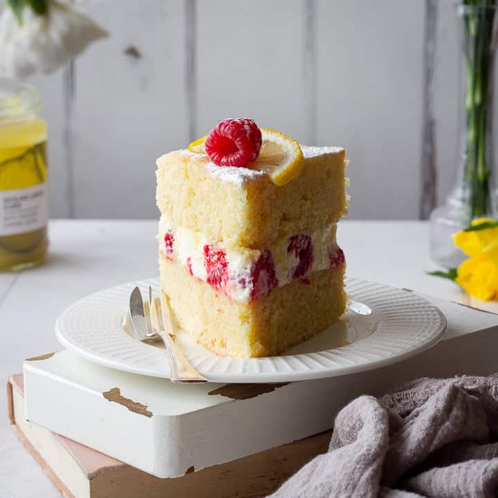 Front view of a slice of lemon and raspberry cake on a plate.