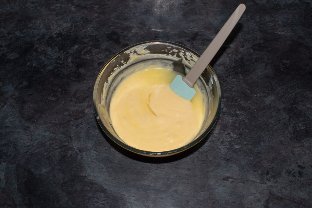 Lemon custard in a bowl with lemon juice being added