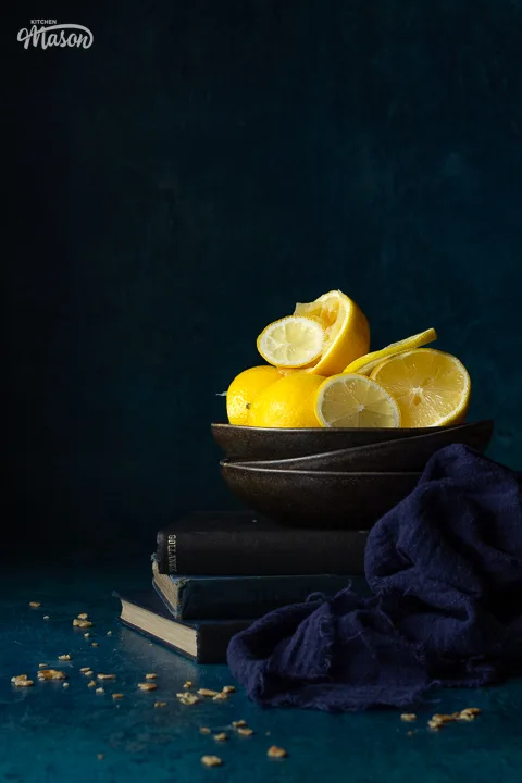 Whole, squeezed and sliced lemons in a bowl on stacked books