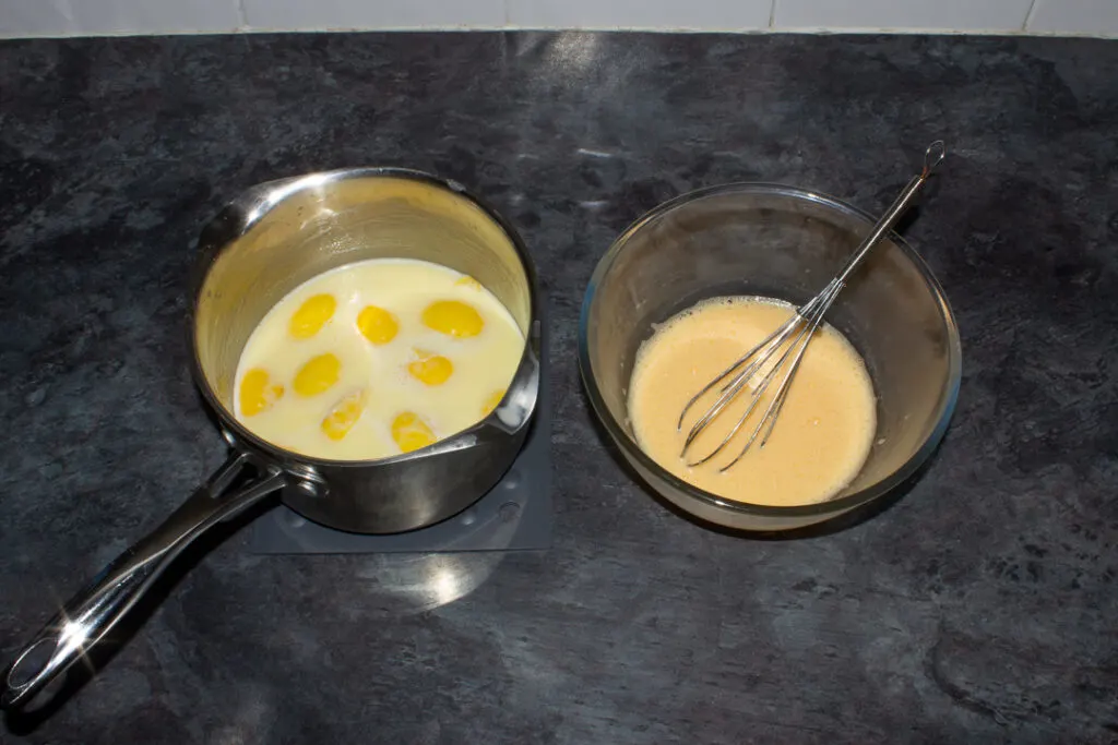 Hot lemon cream being poured over egg yolks and whisked