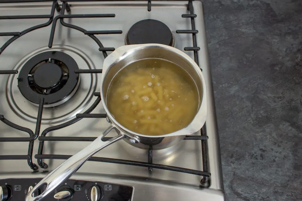 Pasta being cooked in a saucepan of boiling water