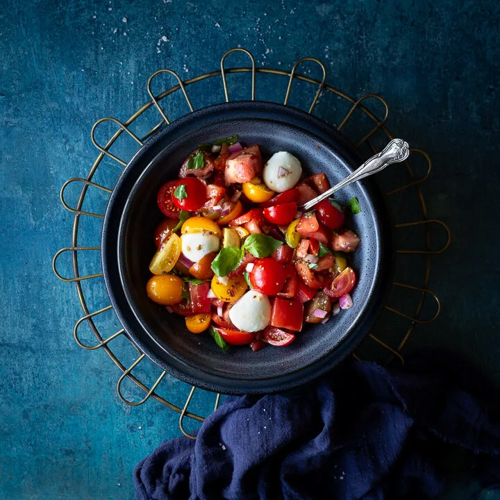 Tomato salad with mozzarella pearls in a blue bowl