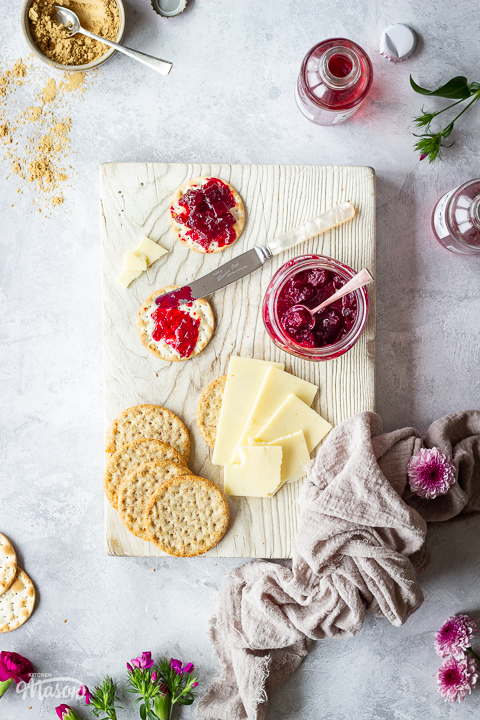 Beetroot chutney on a chopping board with cheese and crackers