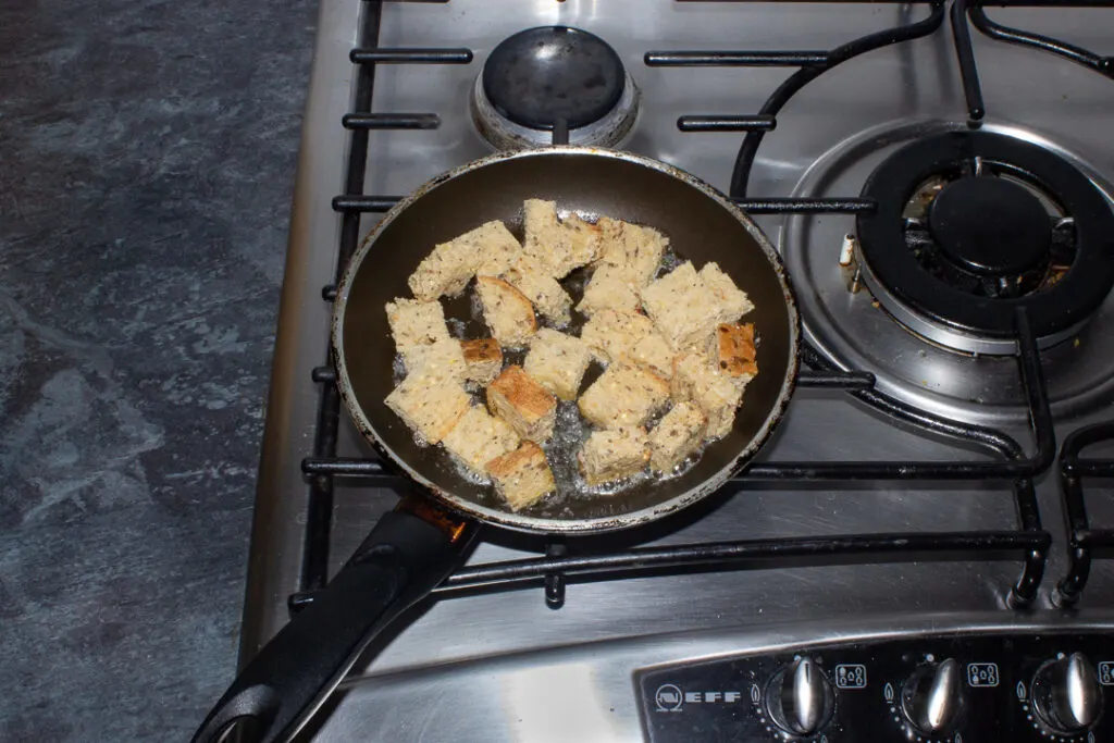 cubes of bread frying in a pan