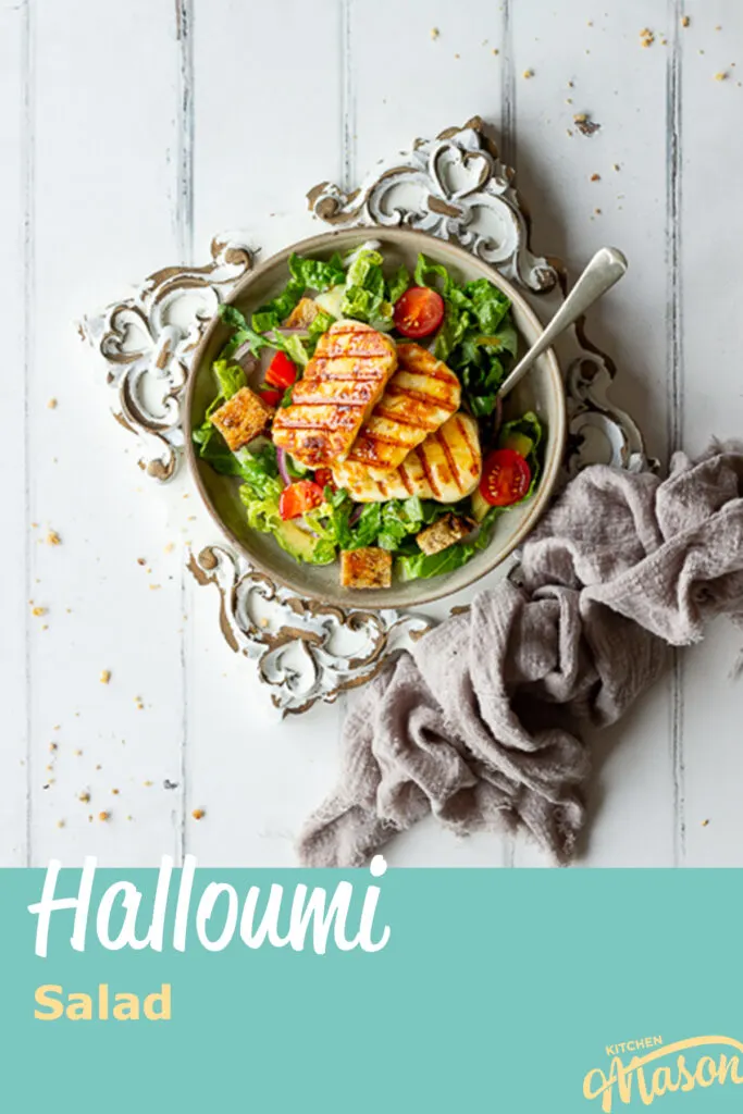 A plate of salad on a decorative wooden board. A text overlay says 'halloumi salad'.