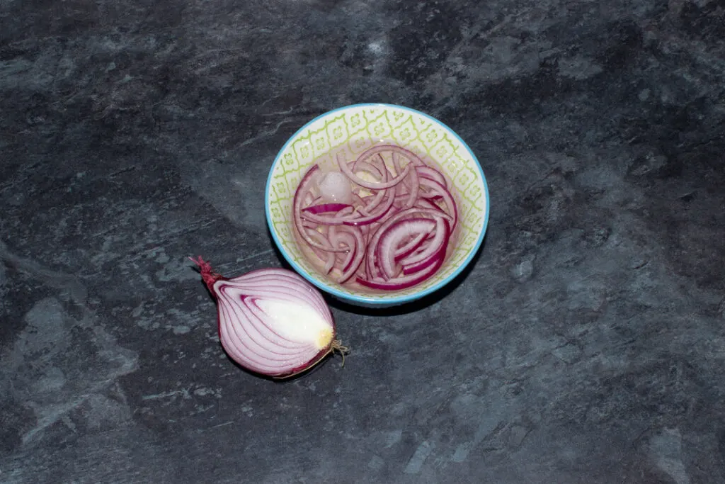 Sliced red onion soaking in ice cold water
