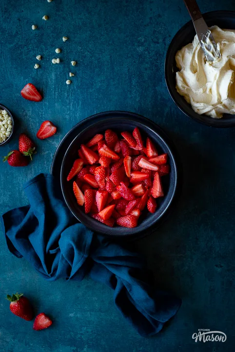 A bowl of sliced strawberries with a napkin