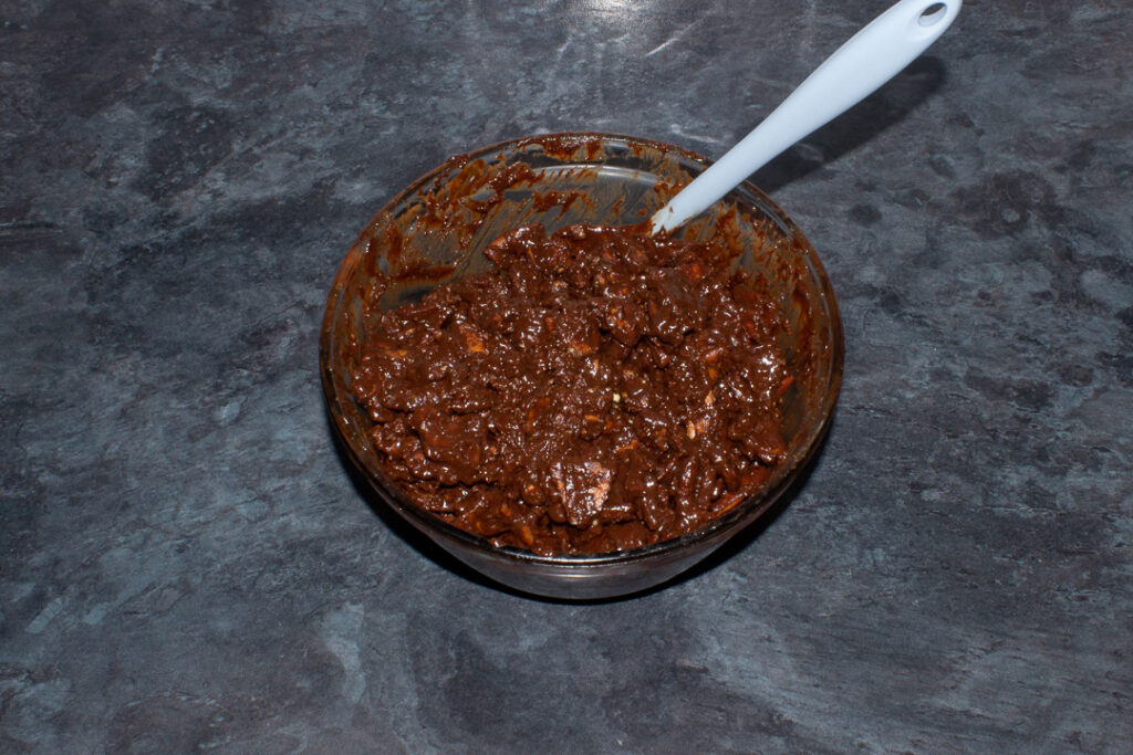 A melted chocolate mixture and crushed rich tea biscuits mixed together in a bowl