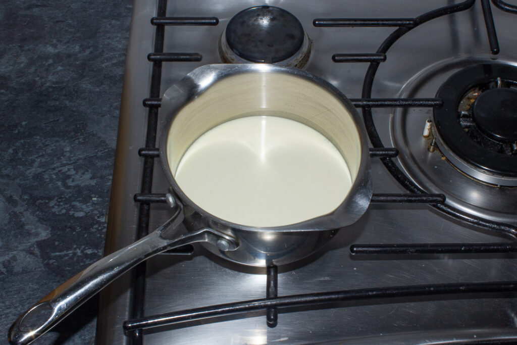 Cream being heated in a saucepan over a low heat