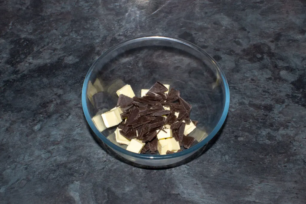 Broken chocolate and cubed butter in a glass bowl