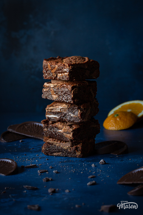 Chocolate orange brownies in a stack with orange slices in the background