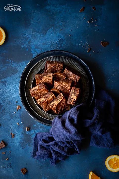 Terry's chocolate orange brownies on stacked plates with a blue napkin
