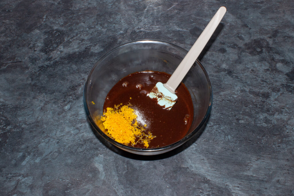 Orange zest being added to brownie batter in a bowl