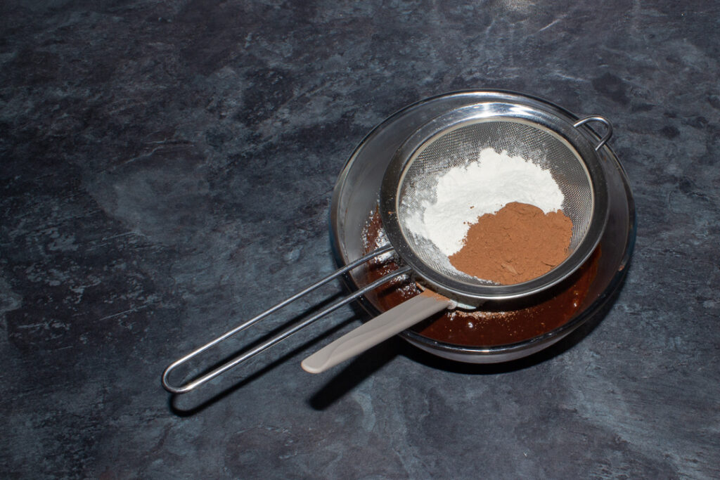 Flour and cocoa powder being added to brownie batter