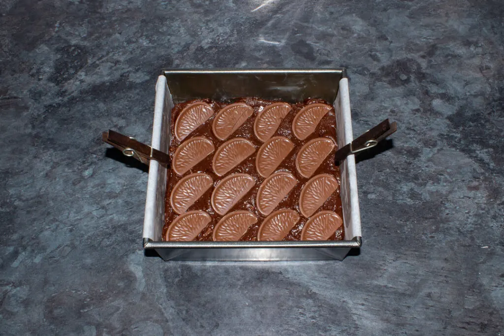 Terry's chocolate orange segments pressed into the top of brownie batter in a lined tin