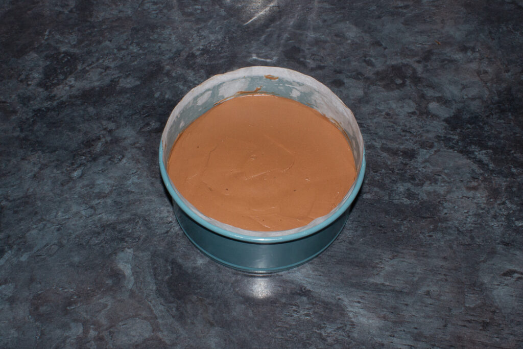 A no bake chocolate orange cheesecake in the tin ready to be chilled