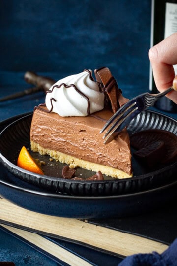 Side view of someone forking a slice of chocolate orange cheesecake