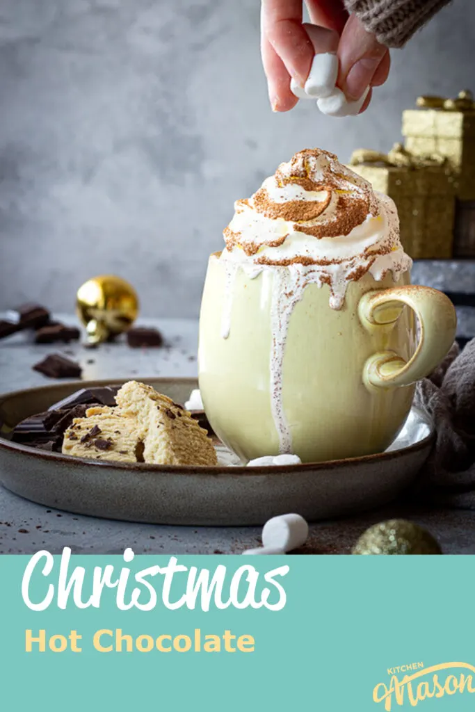 Someone topping a festive hot chocolate with marshmallows