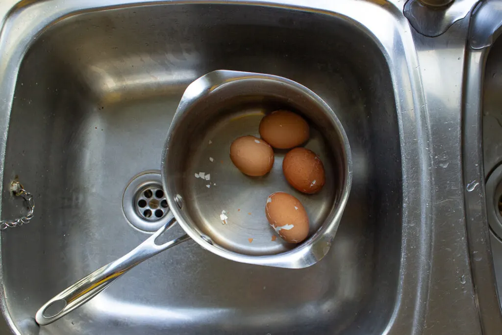 Cracked eggs in a saucepan of cold water