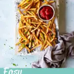 Air fryer French fries on a paper lined board with ketchup
