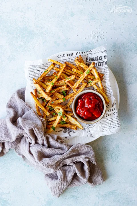 A paper lined plate of air fryer french fries with a napkin