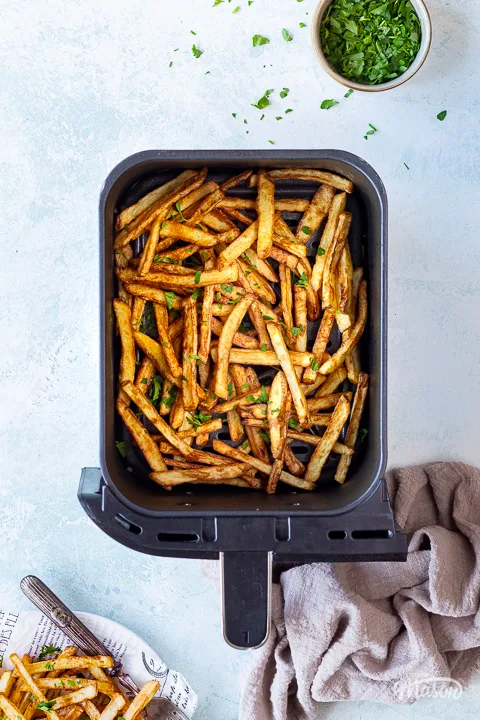 An air fryer basket filled with air fried fries