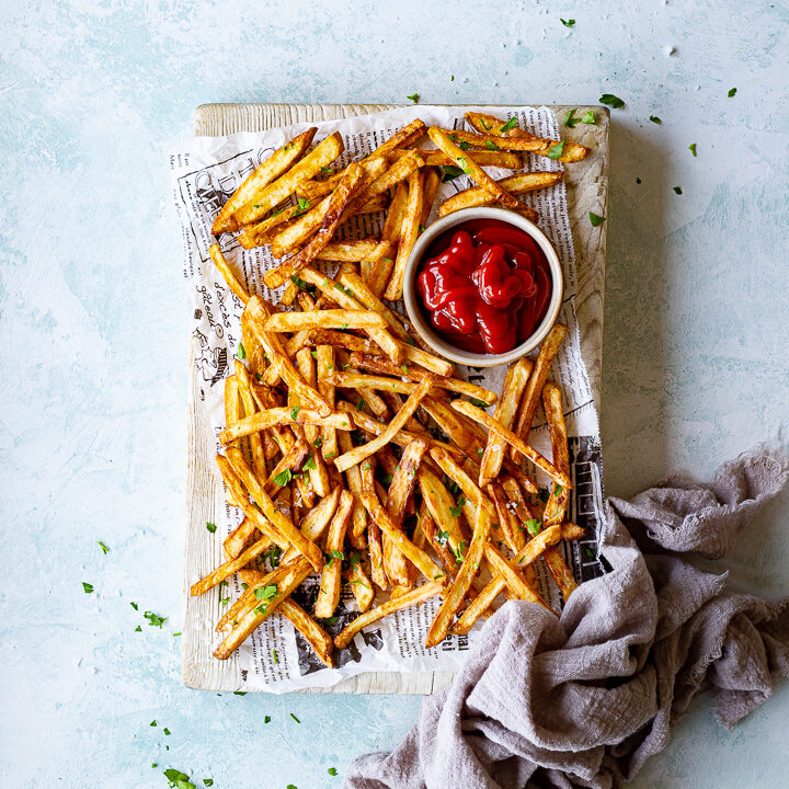 Air fryer fries on a paper lined board with ketchup
