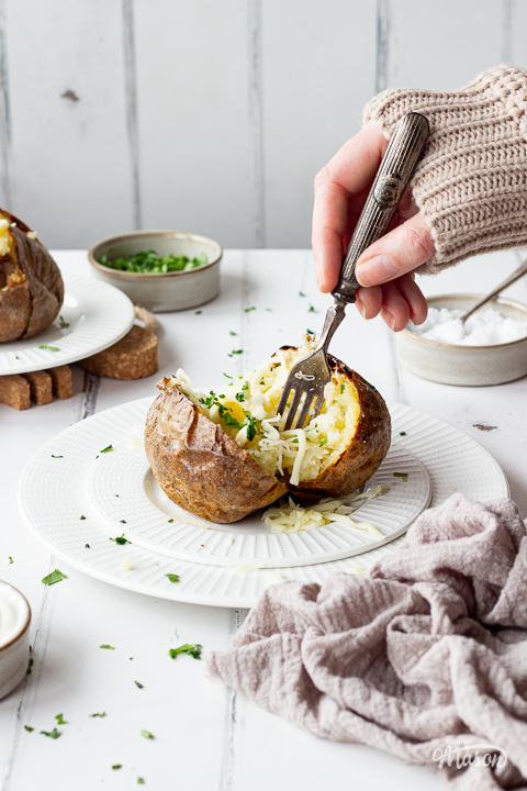 Someone forking a Ninja air fryer jacket potato with cheese