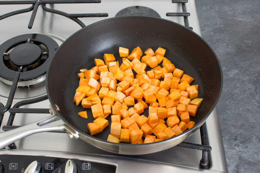 Cubed sweet potato frying in a pan