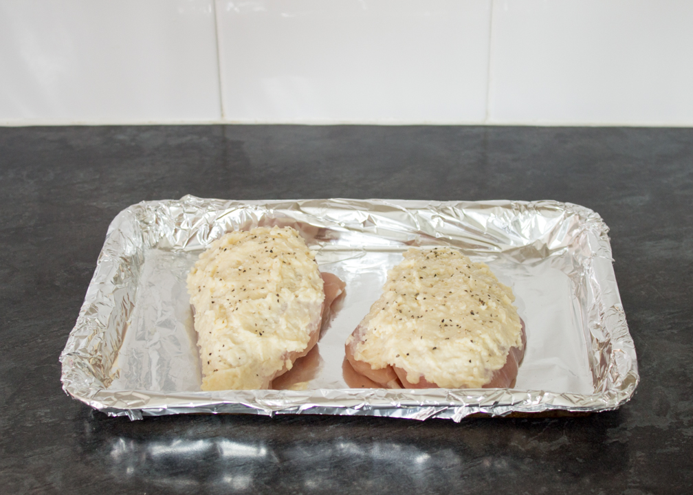 Two chicken breasts topped with mayonnaise, parmesan and seasoning