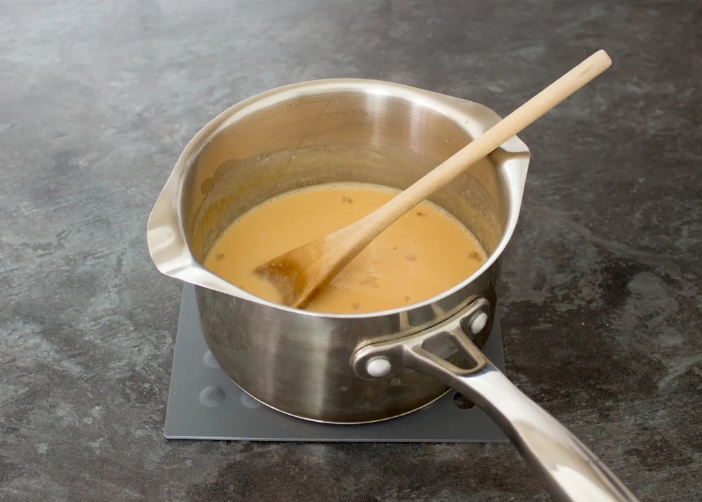 Caramel with eggs beaten into it in a saucepan