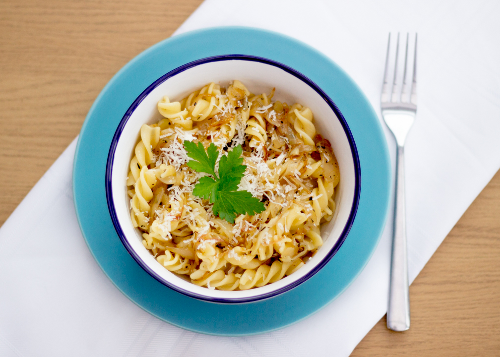 Caramelised onion pasta in a bowl topped with parmesan cheese