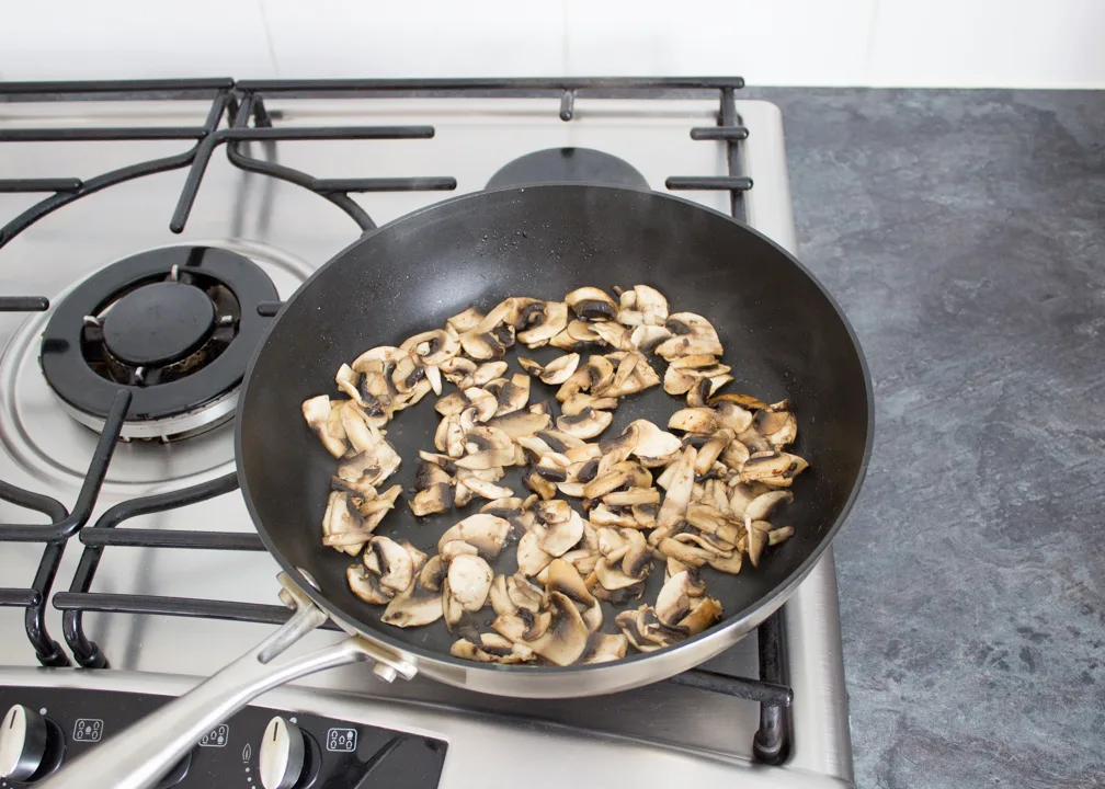 Sliced mushrooms frying in a pan