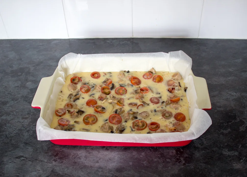 Uncooked full English frittata in a lined ovenproof dish