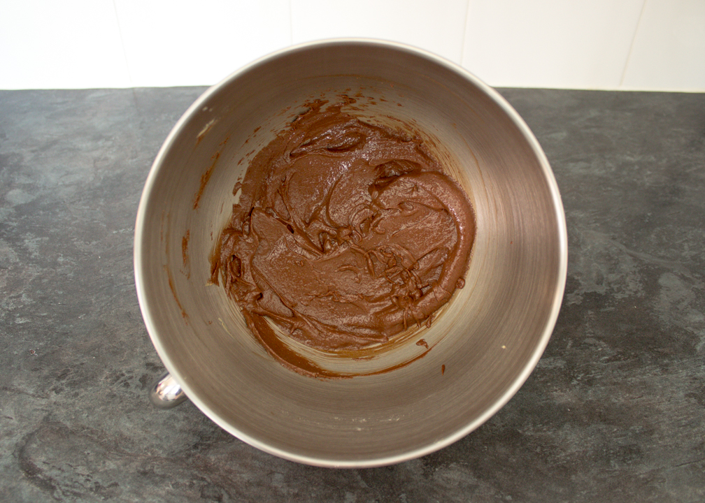 Wet chocolate thumbprint cookie dough ingredients beaten together in a stand mixer bowl