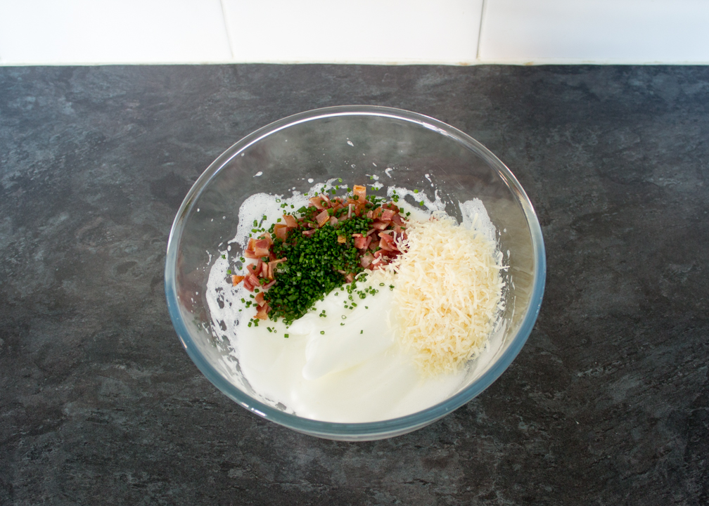 Chopped bacon, chives and parmesan in a bowl with whipped egg whites