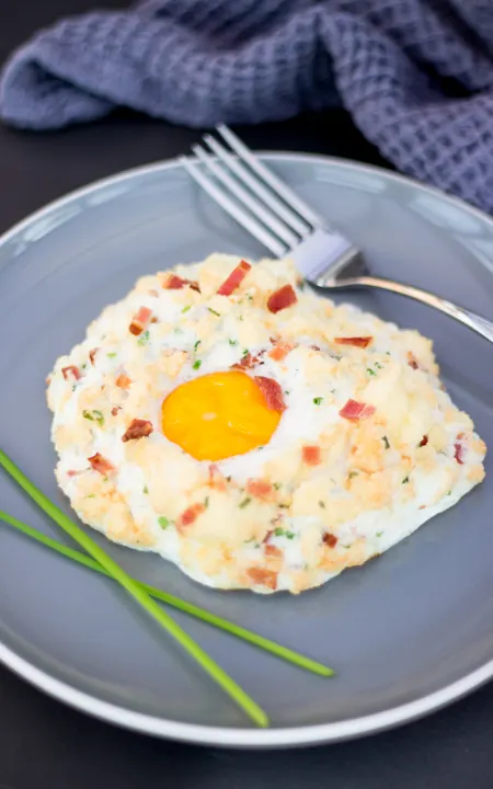 Bacon chive parmesan eggs in clouds on a plate with a fork