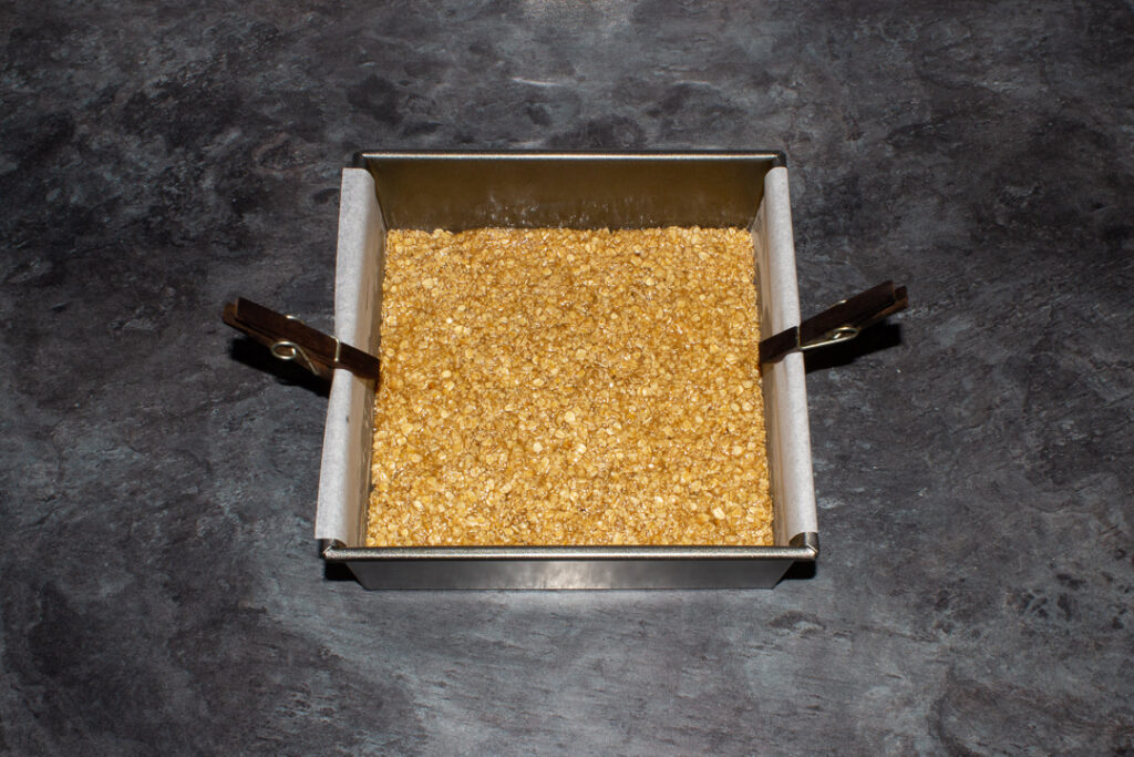 Unbaked flapjack pressed into a lined square baking tin