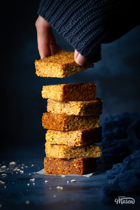 Someone taking a bar of chewy flapjack from the top of a stack