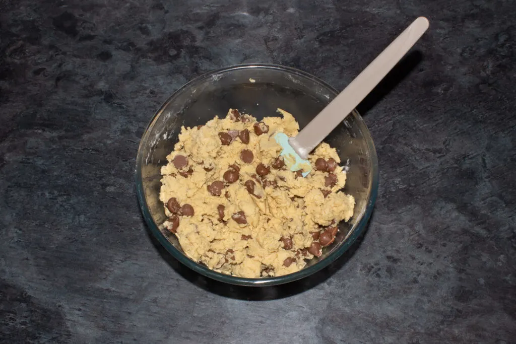 Chocolate chip cookie dough in a mixing bowl with a spatula