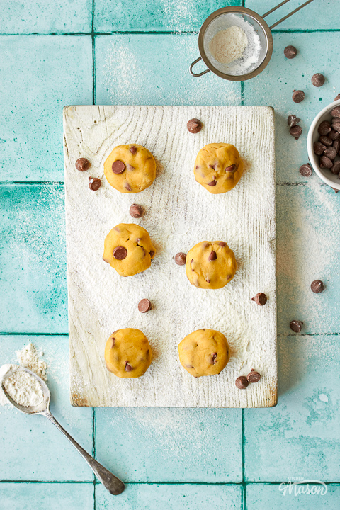 Cookie dough balls on a lightly floured wooden board